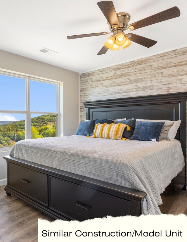 bedroom with hardwood / wood-style flooring, a tile fireplace, and ceiling fan