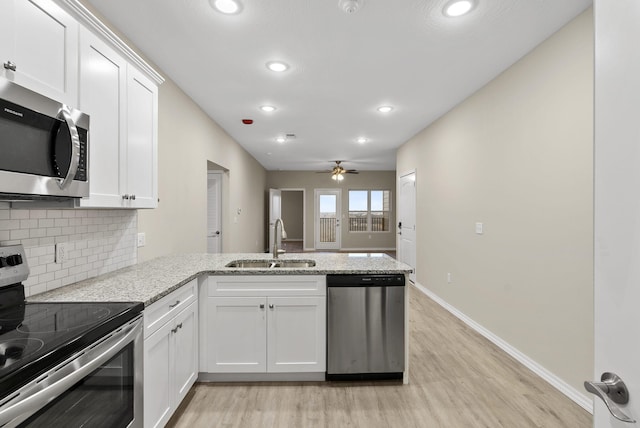 kitchen with sink, appliances with stainless steel finishes, kitchen peninsula, and white cabinets