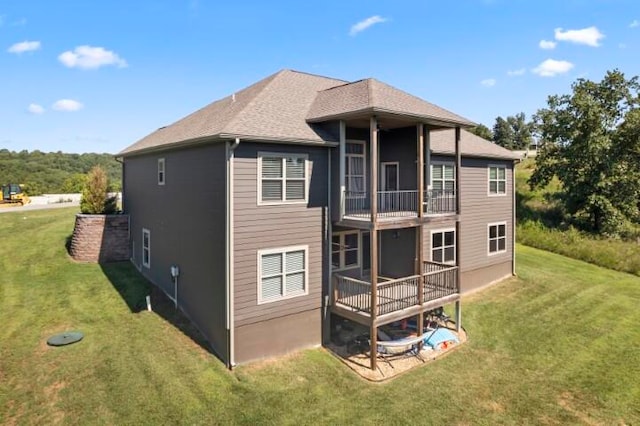 back of house featuring a balcony and a lawn