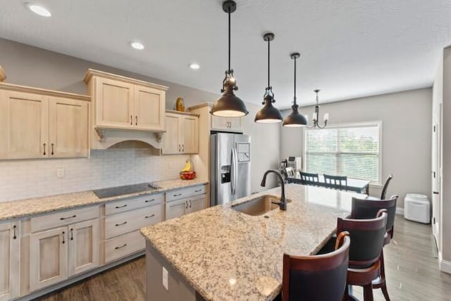 kitchen with stainless steel refrigerator with ice dispenser, a kitchen island with sink, dark wood-type flooring, and sink