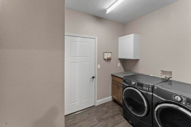 laundry room featuring cabinets, a textured ceiling, dark hardwood / wood-style flooring, and washing machine and dryer