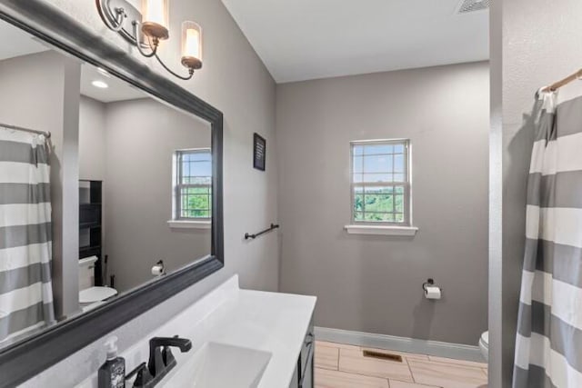 bathroom with hardwood / wood-style flooring, a healthy amount of sunlight, vanity, and toilet