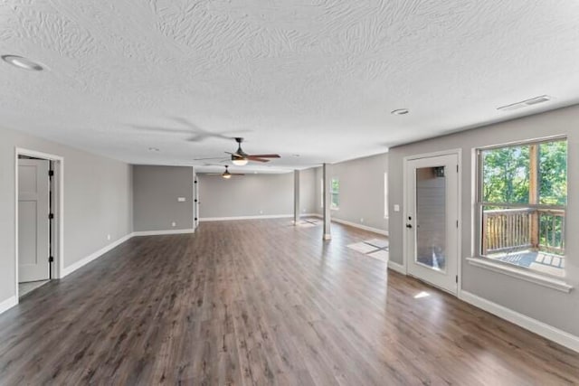 unfurnished living room featuring ceiling fan, a textured ceiling, and dark hardwood / wood-style flooring