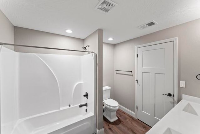 full bathroom featuring vanity, toilet, tub / shower combination, a textured ceiling, and hardwood / wood-style floors