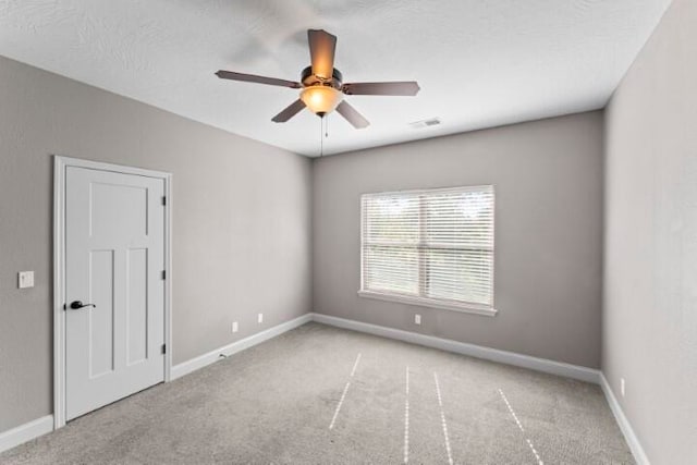 spare room featuring light carpet, ceiling fan, and a textured ceiling