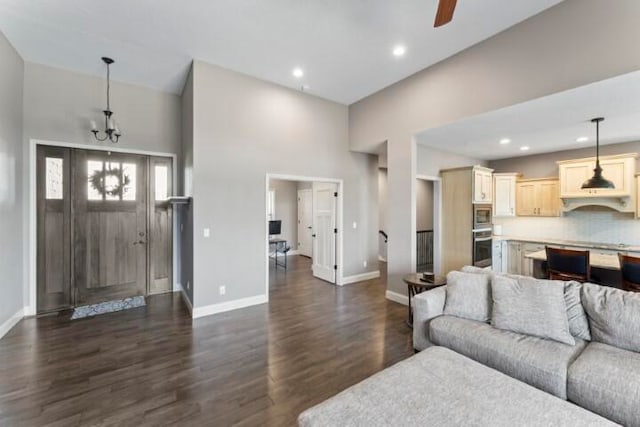 living room featuring ceiling fan with notable chandelier, dark hardwood / wood-style floors, and a high ceiling