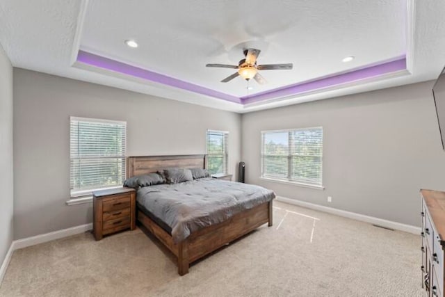 carpeted bedroom featuring ceiling fan and a raised ceiling