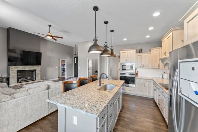 kitchen featuring dark wood-type flooring, decorative light fixtures, sink, an island with sink, and appliances with stainless steel finishes