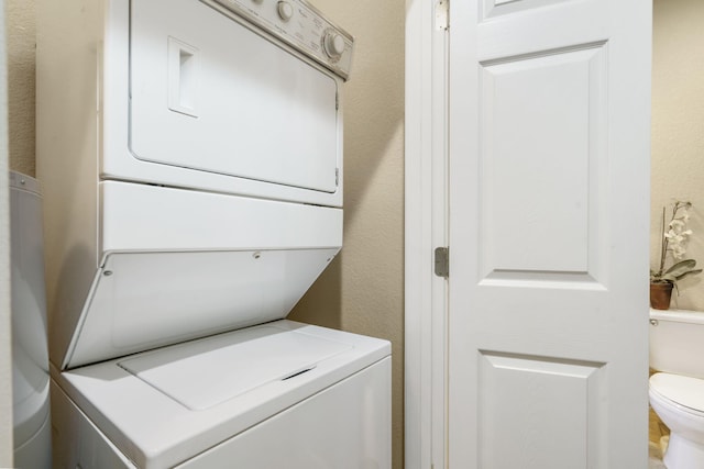 clothes washing area with stacked washing maching and dryer