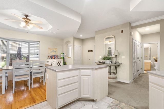 kitchen featuring ceiling fan, white cabinets, a kitchen island, and light carpet