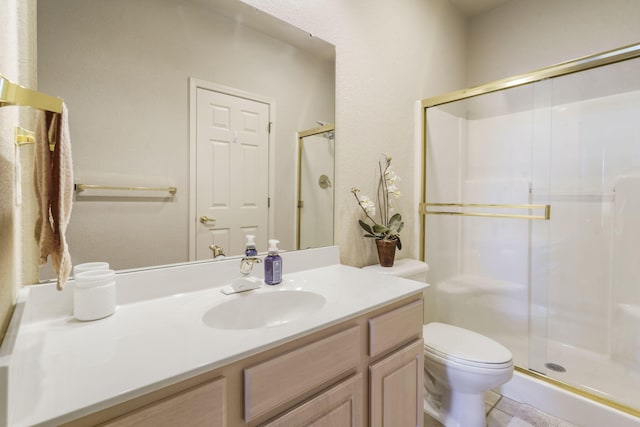 bathroom with vanity, toilet, and a shower with door