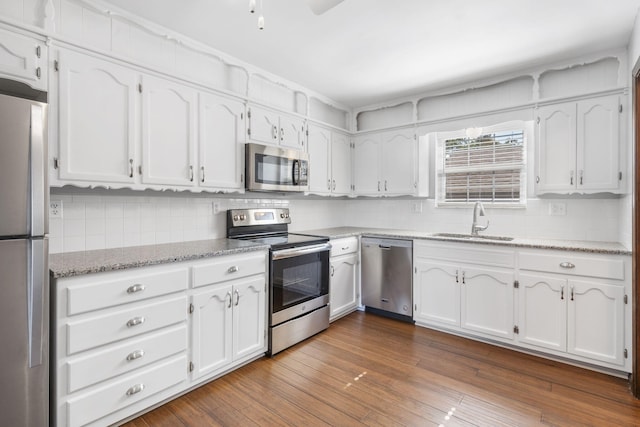 kitchen featuring appliances with stainless steel finishes, tasteful backsplash, a sink, and white cabinetry