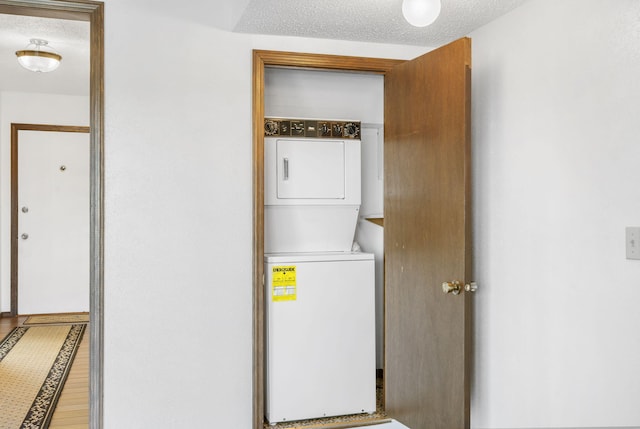 washroom with stacked washing maching and dryer, wood finished floors, and laundry area