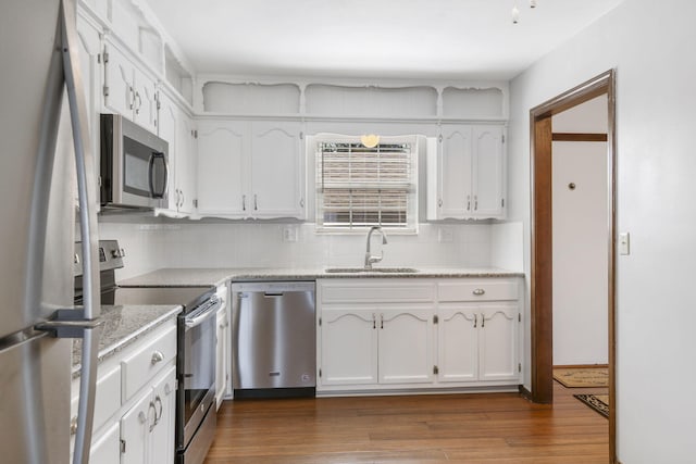 kitchen with decorative backsplash, stainless steel appliances, a sink, and white cabinetry