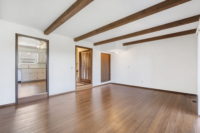 empty room featuring beamed ceiling, hardwood / wood-style floors, sink, and ceiling fan