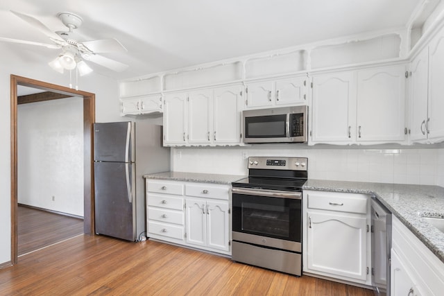 kitchen featuring white cabinets, backsplash, appliances with stainless steel finishes, and light wood finished floors
