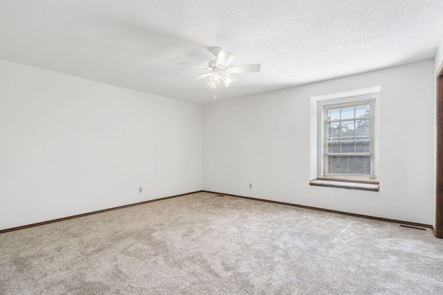 empty room with a ceiling fan, baseboards, carpet floors, and a textured ceiling