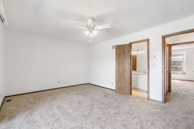 unfurnished bedroom with ceiling fan, light colored carpet, a textured ceiling, and connected bathroom