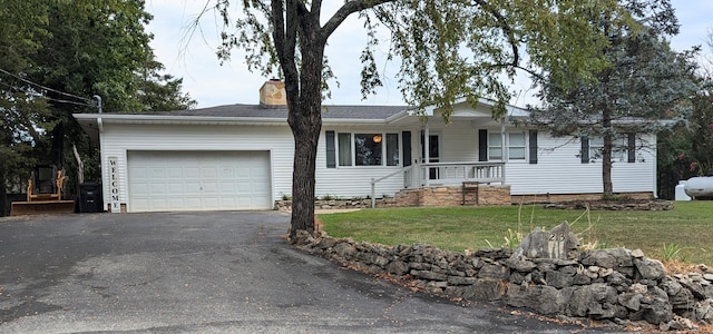 ranch-style home featuring covered porch, a garage, and a front lawn