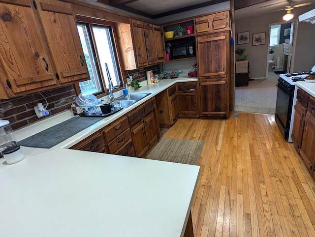 kitchen with sink, backsplash, light hardwood / wood-style flooring, and black appliances