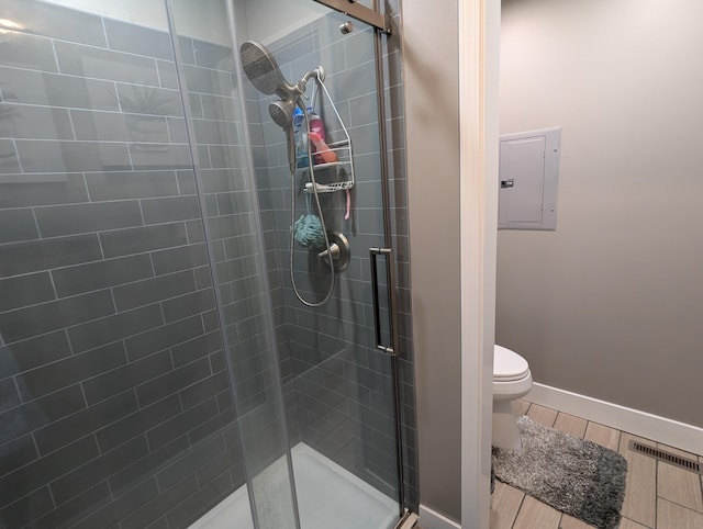 bathroom with electric panel, an enclosed shower, and toilet