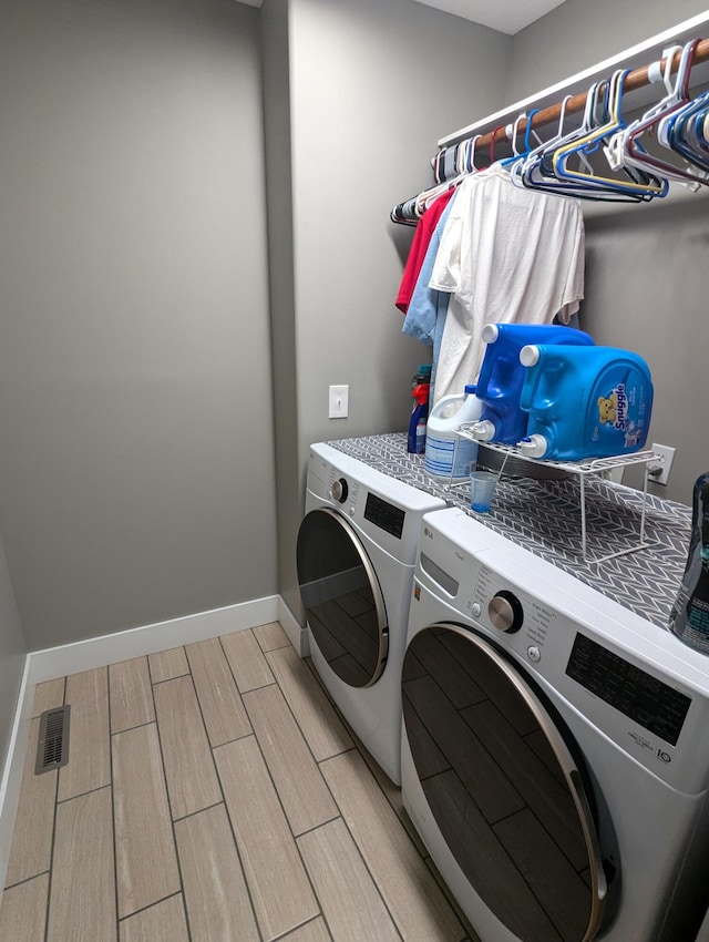 clothes washing area featuring washing machine and dryer and light hardwood / wood-style flooring