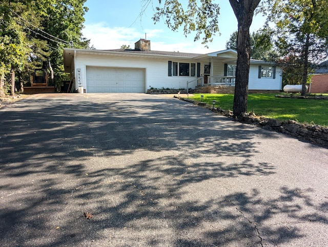 ranch-style home with a front lawn, covered porch, and a garage