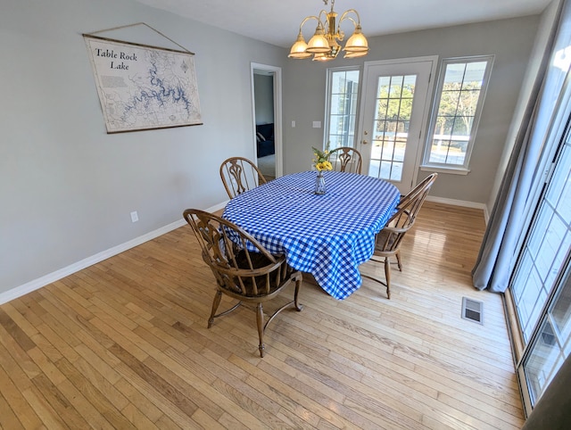 dining space with light wood-type flooring and a notable chandelier