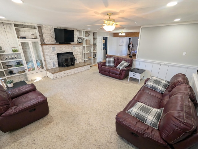 carpeted living room with ceiling fan, built in features, a fireplace, and wooden walls