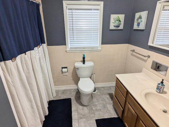 bathroom featuring vanity, tile patterned floors, toilet, tile walls, and walk in shower