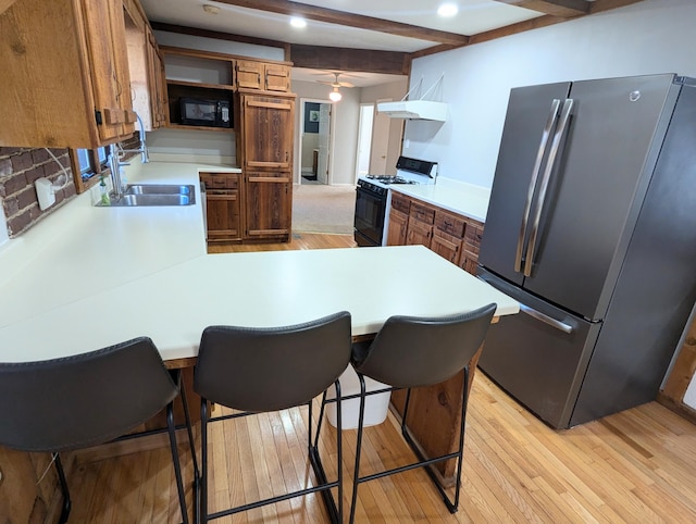 kitchen featuring a breakfast bar area, kitchen peninsula, black appliances, and light hardwood / wood-style floors