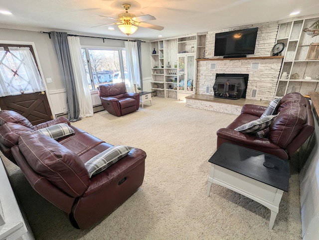 living room featuring a stone fireplace, ceiling fan, built in features, and carpet