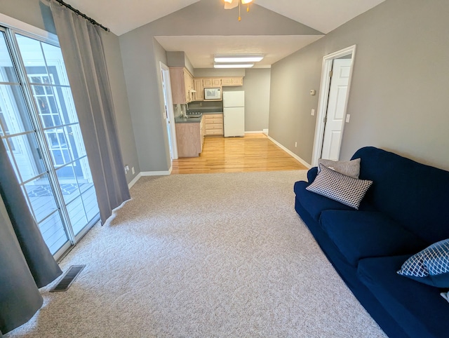 living room featuring ceiling fan, light hardwood / wood-style flooring, and vaulted ceiling