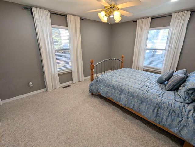 carpeted bedroom featuring ceiling fan and multiple windows