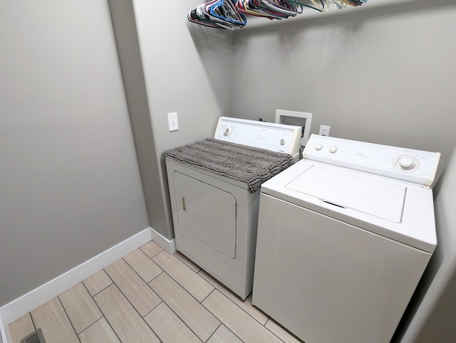 laundry area with light hardwood / wood-style flooring and washer and clothes dryer