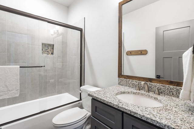 full bathroom with bath / shower combo with glass door, vanity, and toilet