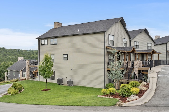 view of property exterior featuring a yard, central air condition unit, and covered porch