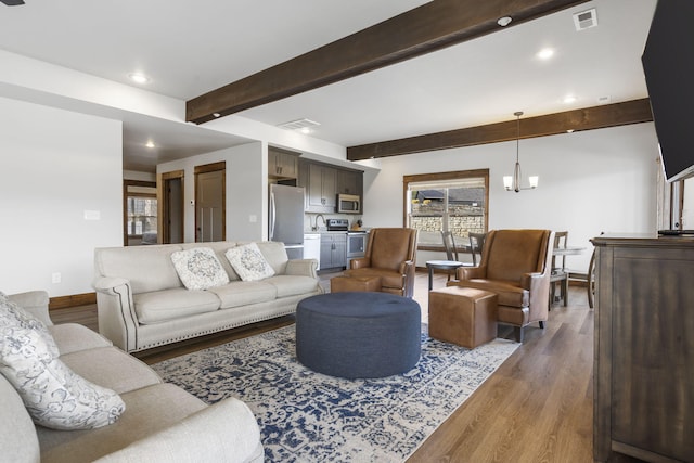 living room featuring a notable chandelier, beam ceiling, dark wood-type flooring, and sink