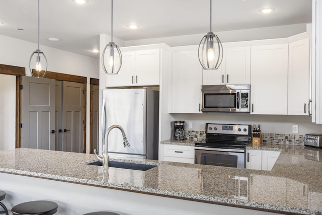 kitchen featuring hanging light fixtures, stainless steel appliances, and white cabinets