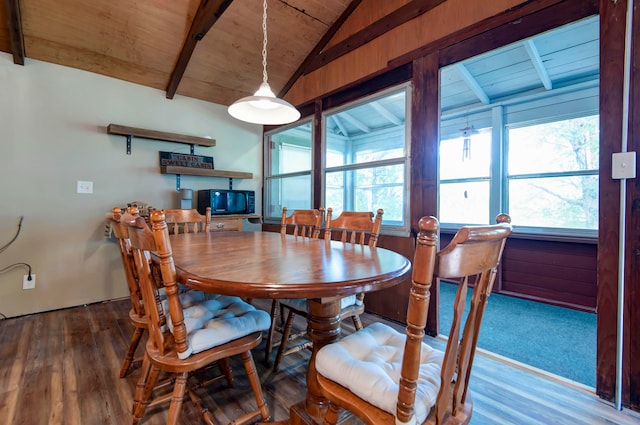 dining space with vaulted ceiling with beams, wooden walls, hardwood / wood-style floors, and wood ceiling