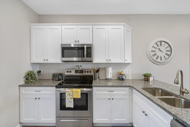 kitchen featuring light stone counters, tasteful backsplash, sink, white cabinetry, and appliances with stainless steel finishes