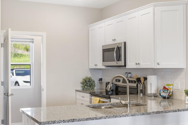 kitchen with white cabinets, appliances with stainless steel finishes, and light stone counters