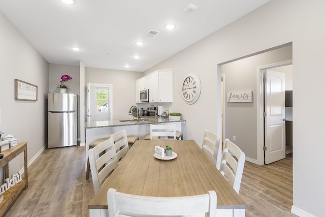 dining space with light hardwood / wood-style floors and sink