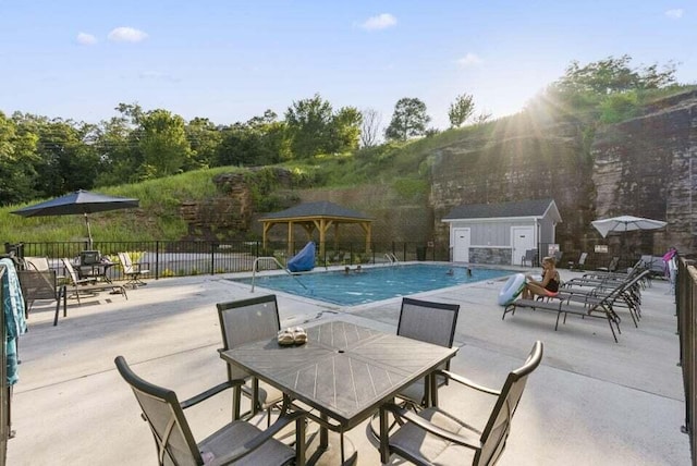 view of pool featuring a gazebo, a storage unit, and a patio area