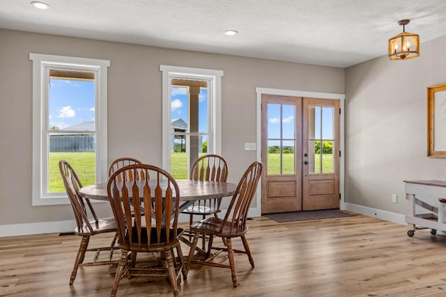 dining room with a notable chandelier, light hardwood / wood-style flooring, and french doors