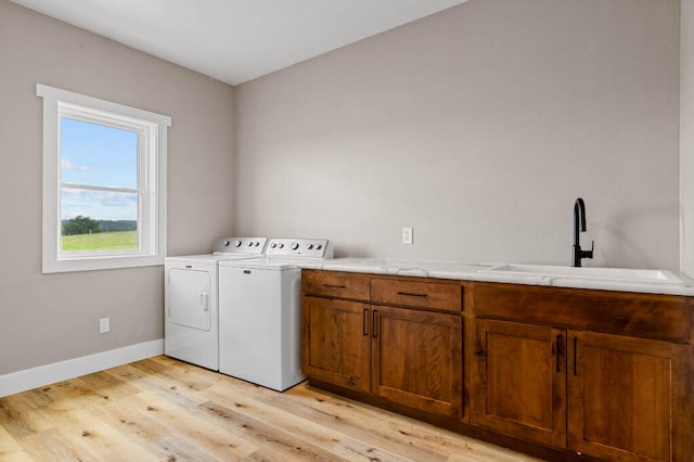 washroom with separate washer and dryer, light hardwood / wood-style floors, cabinets, and sink