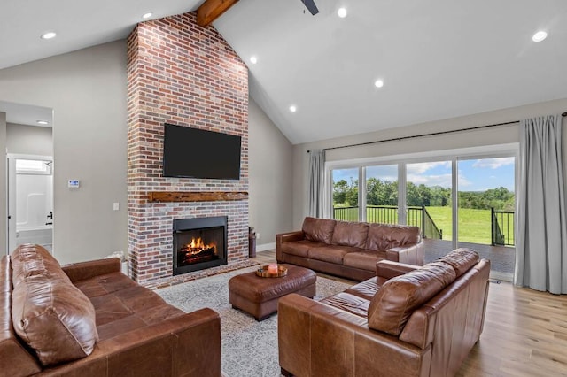 living room featuring beamed ceiling, high vaulted ceiling, light wood-style flooring, recessed lighting, and a brick fireplace