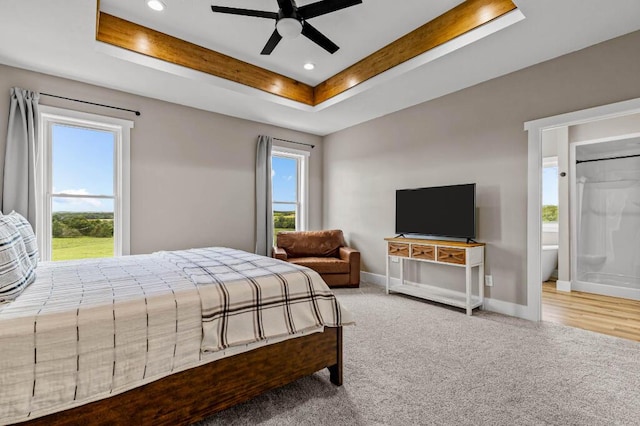 carpeted bedroom featuring recessed lighting, a tray ceiling, baseboards, and multiple windows