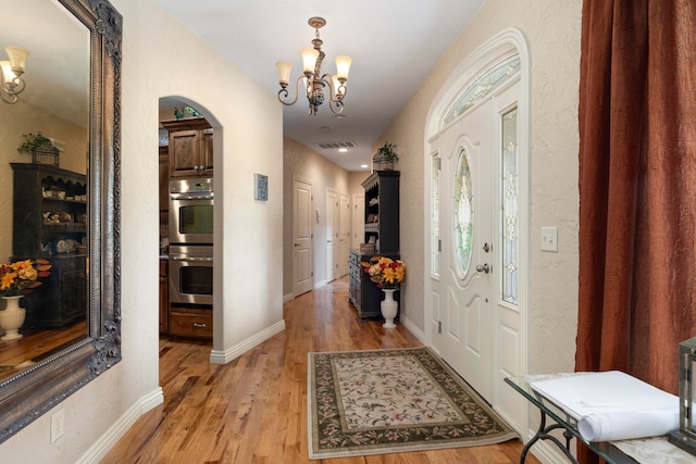 entryway with an inviting chandelier and light wood-type flooring