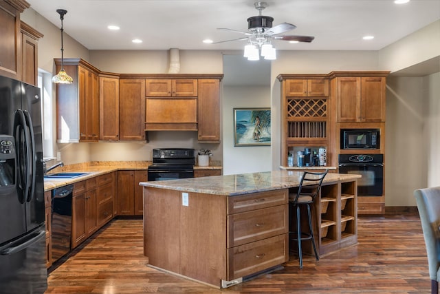 kitchen with pendant lighting, a kitchen island, a breakfast bar, dark hardwood / wood-style floors, and black appliances